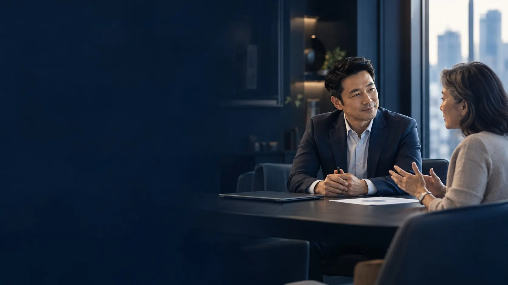 An insurance advisor listening to a customer across a meeting table.